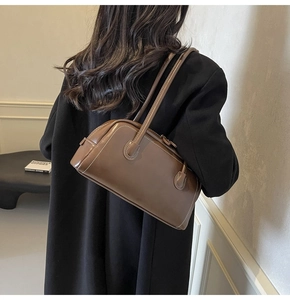 Detail of vintage brown shoulder bag with white contrast stitching and sleek synthetic leather
