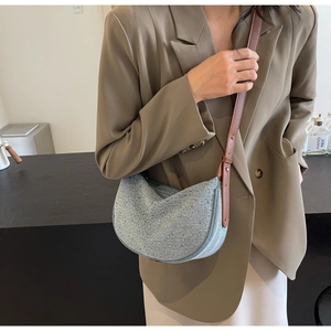 Detail of light blue crescent bag with silver studs and brown leather shoulder strap