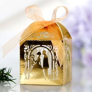 Detail of gold laser-cut favor box featuring couple silhouette and champagne ribbon