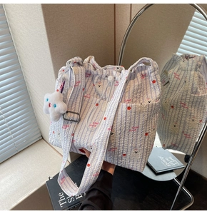 Détail du sac cabas en nylon à rayures bleues avec imprimés cerises et peluche étoile