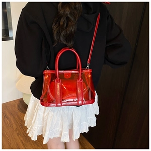 Détail d'un sac seau transparent rouge avec poignées en cuir et pochette sur mannequin