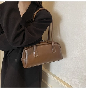 Close-up of brown leather Boston bag featuring elegant white contrast stitching detail