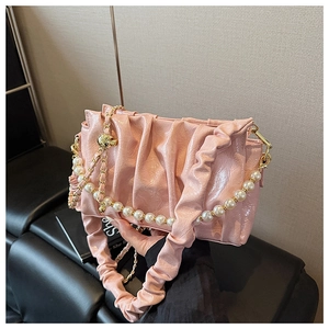 Detailed view of pink pleated faux leather bag with oversized pearl and gold chain strap