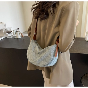 Dettaglio della borsa hobo in denim con strass e tracolla in pelle marrone sulla spalla