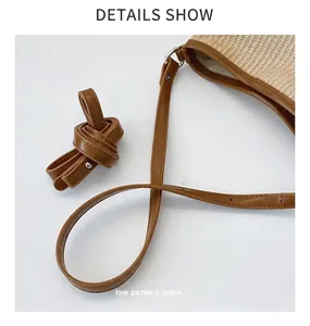 Close-up of woven straw handbag with adjustable brown leather strap and silver hardware