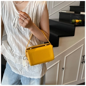 Detail of yellow box handbag with premium leather texture and elegant pearl lace charm