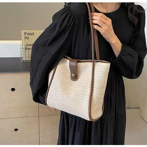 Detail of woven tote bag with contrast leather trim and snap button closure for women