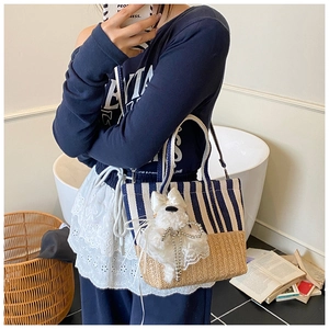 Detail of canvas stripe and straw woven tote bag featuring a cute plush puppy pendant