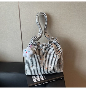 Détail du sac seau en nylon à rayures noires et blanches avec un charme étoile en peluche