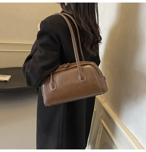 Detail view of brown leather Boston bag with white contrast stitching and slim handles