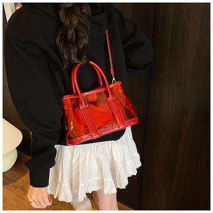Sac seau en PVC rouge tendance porté par un mannequin avec bandoulière pour un look chic