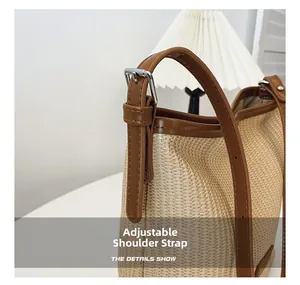Detail of adjustable brown leather shoulder strap on a woven straw handbag