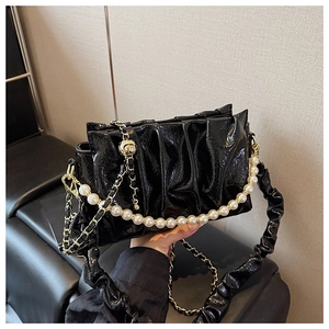 Detailed view of black patent leather pleated cloud bag with elegant pearl chain handle