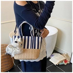 Detail of canvas striped and straw woven tote bag featuring a cute plush puppy pendant