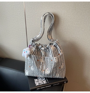 Détail du sac cabas en nylon rayé avec cordon de serrage et breloque nuage peluche
