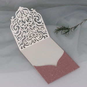 Détail d'invitation découpée au laser avec motif crème évidé et pochette rose pailletée