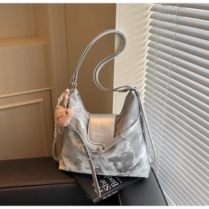 Detail of silver textured hobo bag with wide shoulder strap and plush bear charm decoration