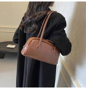 Detail view of a vintage brown underarm bag with white contrast stitching and slim straps