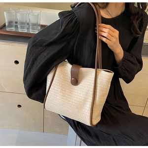 Detail of woven tote bag with brown leather trim and shoulder strap on a model