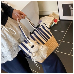 Detail of striped woven tote bag with white plush kitten charm and lace pearl chain