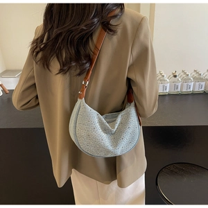 Detail of light blue denim half-moon bag with rhinestones and brown leather strap