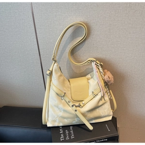 Detail view of cream shoulder bag with plush bear charm and fashion leather logo embossing
