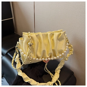 Detail showing the glossy yellow pleated leather texture and large pearl chain decoration