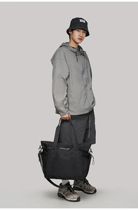 Detail of a black large-capacity travel bag paired with urban outdoor lifestyle clothing