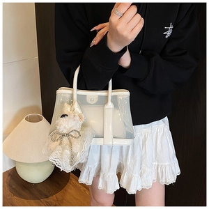 Détail du sac seau transparent avec pochette blanche et charm de chiot en peluche