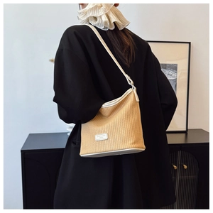 Detailed shot of woven straw tote bag featuring leather straps and brand logo plate