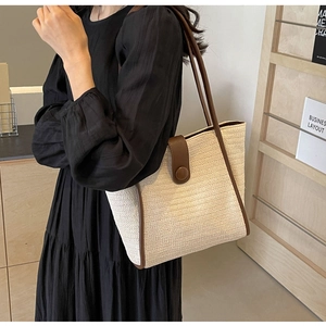 Detail of color-block woven tote bag with brown leather handles on a female model