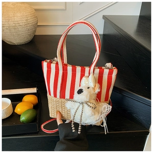 Detail of red stripe canvas tote with woven straw base and cute plush dog charm