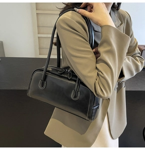 Detail of a black Boston shoulder bag with contrast stitching on a khaki blazer
