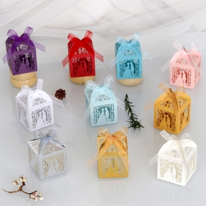 Detail of laser cut wedding favor boxes with bride and groom silhouettes and ribbon