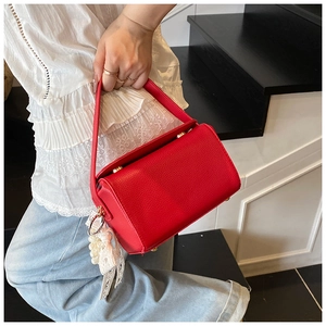 Detail of red faux leather handbag with lace pearl pendant and gold hardware