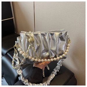 Detail of silver pleated cloud bag with pearl chain handle and gold hardware finish