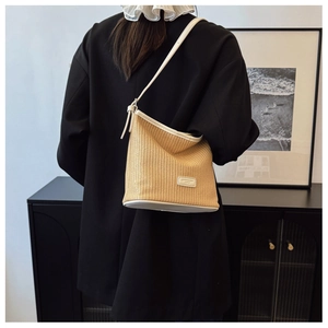 Detail of woven straw bucket bag with cream leather trim shown on a female model