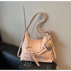 Detailed shot of pink textured shoulder bag with fashion text and cute plush bear charm