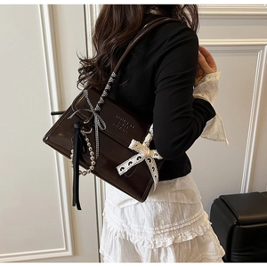 Chocolate glossy shoulder bag with lace bow, pearl chain and ribbon detail on a model