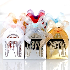Detail of laser-cut wedding favor boxes with bride and groom silhouettes and silk ribbons