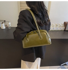 Detail of olive green bowling bag with white stitching and glossy leather texture