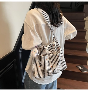 Détail d'un sac bandoulière en nylon rayé avec imprimés mignons et breloque en peluche