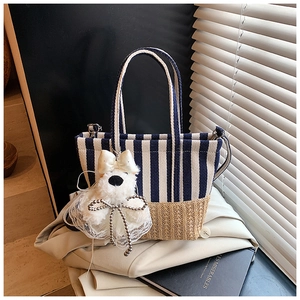 Detail of striped canvas handbag with straw base and cute plush puppy charm