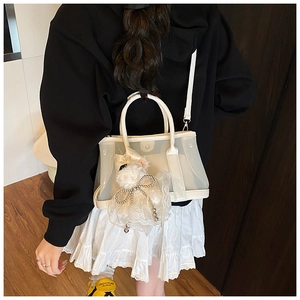 Détail du sac seau en maille blanche avec pendentif nœud en dentelle et bandoulière amovible