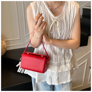 Detail of red pebbled leather mini crossbody bag with white lace tassel and gold clasp