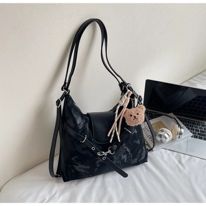 Detail of black splash-ink backpack with teddy bear charm and silk scarf decoration