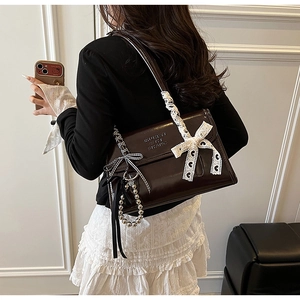 Close-up of vintage dark brown faux leather bag with lace bow and pearl charm detail