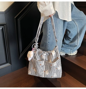 Vue détaillée du grand sac bandoulière rayé en nylon avec broderie et breloque en peluche