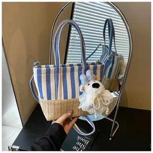 Detail of blue striped canvas tote with woven base and cute plush bear accessory