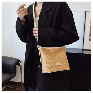 Detailed view of woven straw crossbody bag with white leather trim and brand patch
